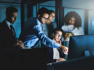 Group of colleagues together looking at a computer screen to illustrate managed IT services