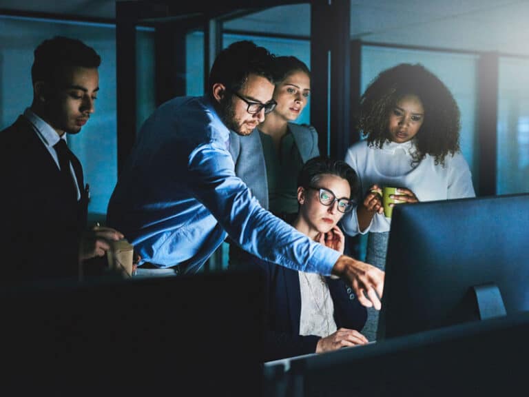 Group of colleagues together looking at a computer screen to illustrate managed IT services