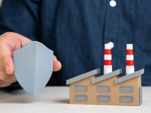 man holds a protective shield near a model building to illustrate what kind of cybersecurity solutions businesses should expect in Charlotte, NC