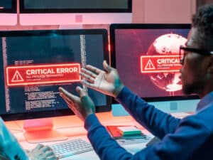 African male programmer staring at a locked computer screen showing one kind of cybersecurity threat