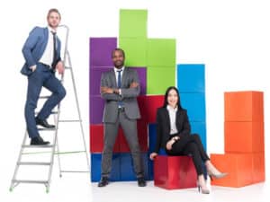 employees on a ladder or by block towers to illustrate scaling efficiently with managed IT services