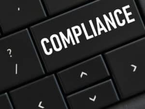 The word COMPLIANCE written over a black keyboard to illustrate the link between computer data and staying HIPAA compliant